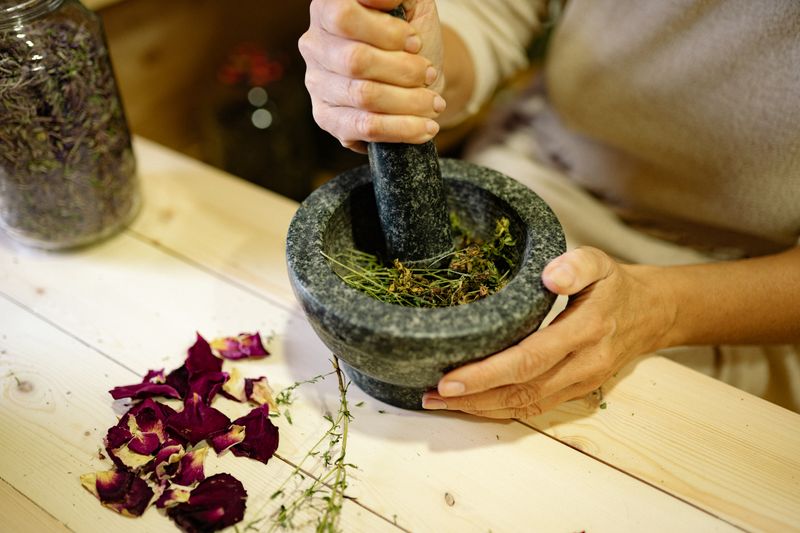 Hands grinding herbs in a stone mortar and pestle
